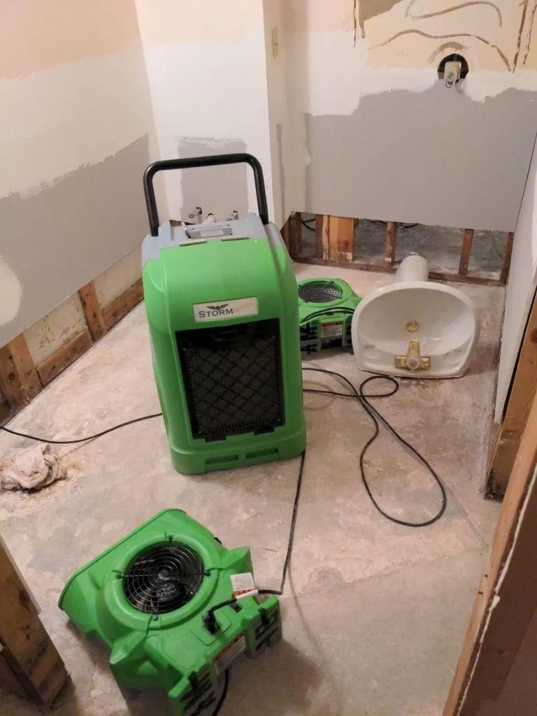 Master Restoration dehumidifier and air mover drying a water-damaged bathroom